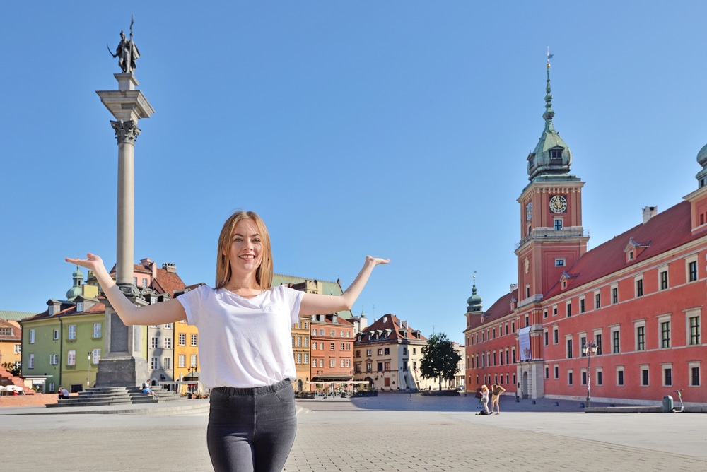 A digital nomad and teacher exploring the historic streets of Warsaw, Poland, near the Royal Castle and Sigismund's Column.