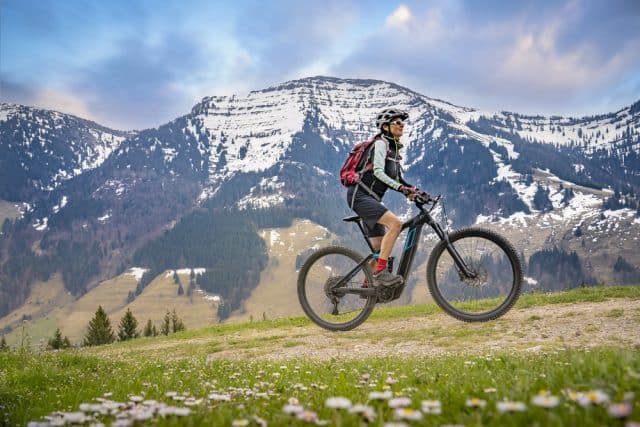 A traveler mountain biking on a trail, relying on sports travel insurance for safety