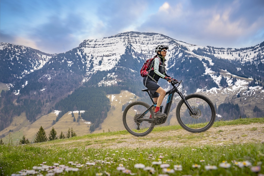 A traveler mountain biking on a trail, relying on sports travel insurance for safety
