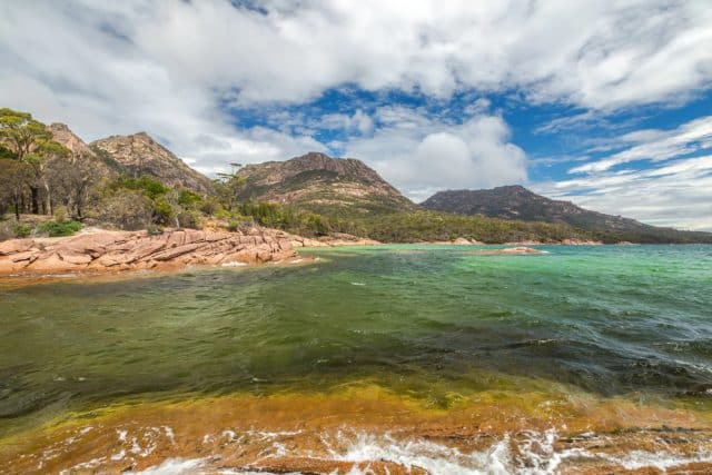 Pristine coastline of the Freycinet Peninsula, Tasmania, with granite peaks and turquoise water, one of the extraordinary places worth rerouting for in Australia.