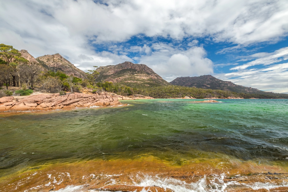 Pristine coastline of the Freycinet Peninsula, Tasmania, with granite peaks and turquoise water, one of the extraordinary places worth rerouting for in Australia.